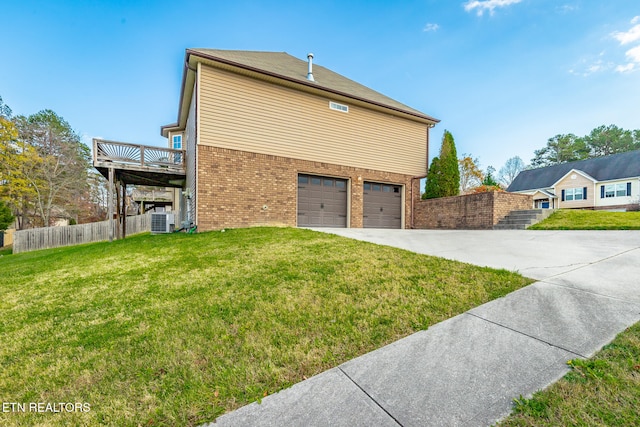 view of side of property featuring a lawn, central AC unit, and a garage