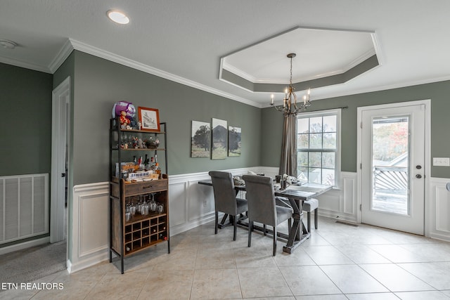 dining area with a raised ceiling, crown molding, a chandelier, and light tile patterned flooring