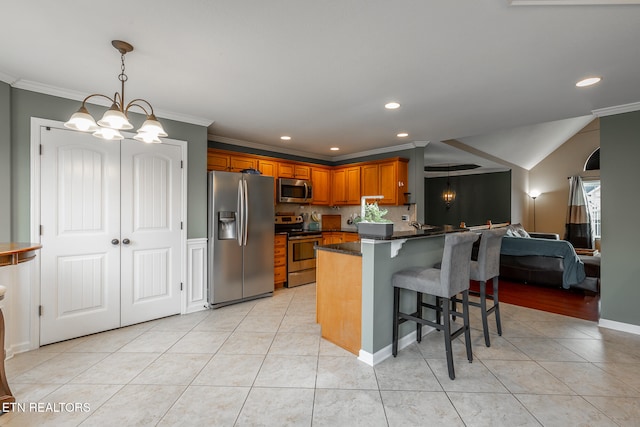 kitchen featuring appliances with stainless steel finishes, a kitchen bar, a notable chandelier, light tile patterned floors, and crown molding