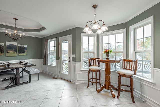 tiled dining room featuring a chandelier, crown molding, a raised ceiling, and plenty of natural light