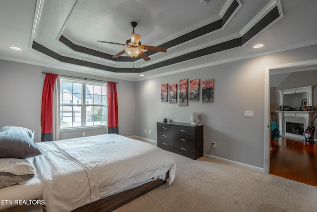 bedroom featuring ceiling fan, a tray ceiling, ornamental molding, and carpet flooring