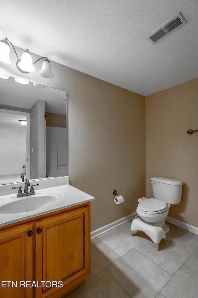 bathroom with toilet, tile patterned flooring, a textured ceiling, and vanity