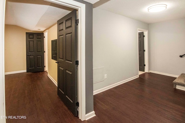 corridor featuring dark hardwood / wood-style floors, a textured ceiling, and vaulted ceiling