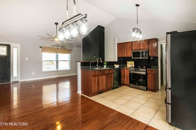 kitchen with appliances with stainless steel finishes, sink, pendant lighting, light hardwood / wood-style flooring, and high vaulted ceiling