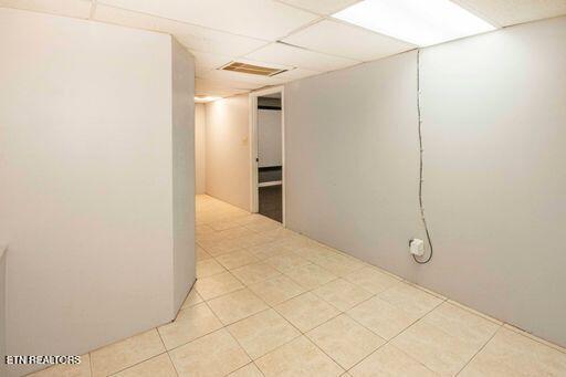 basement featuring a drop ceiling and light tile patterned flooring