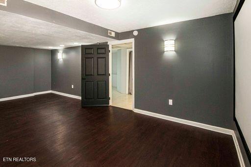 basement featuring a textured ceiling and dark hardwood / wood-style floors