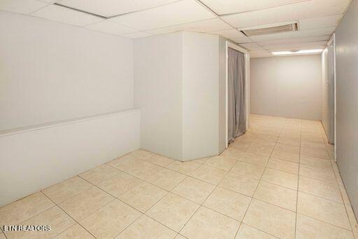 hallway with light tile patterned floors and a paneled ceiling