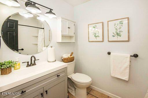 bathroom with toilet, vanity, and tile patterned floors