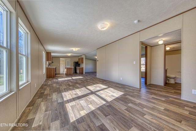 unfurnished living room featuring a textured ceiling and dark hardwood / wood-style flooring