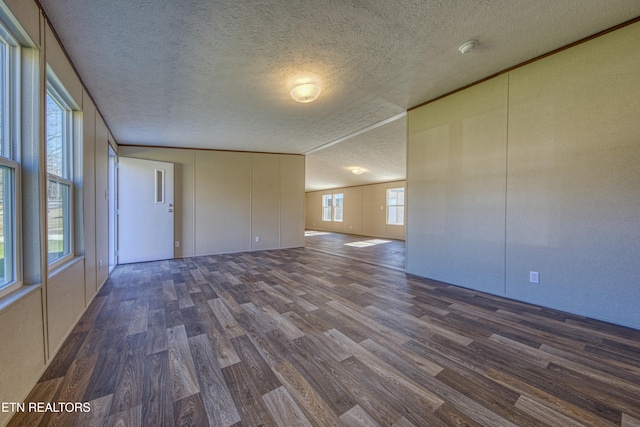 empty room with a textured ceiling and dark wood-type flooring