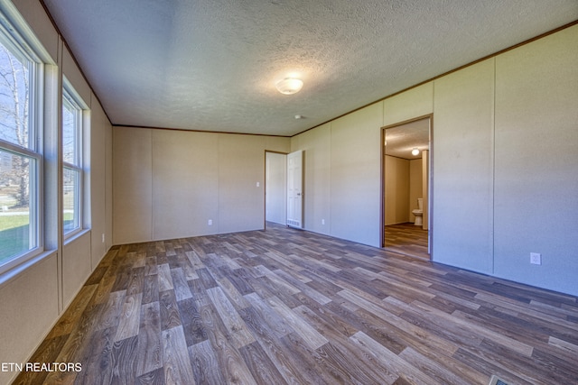 empty room with hardwood / wood-style floors and a textured ceiling