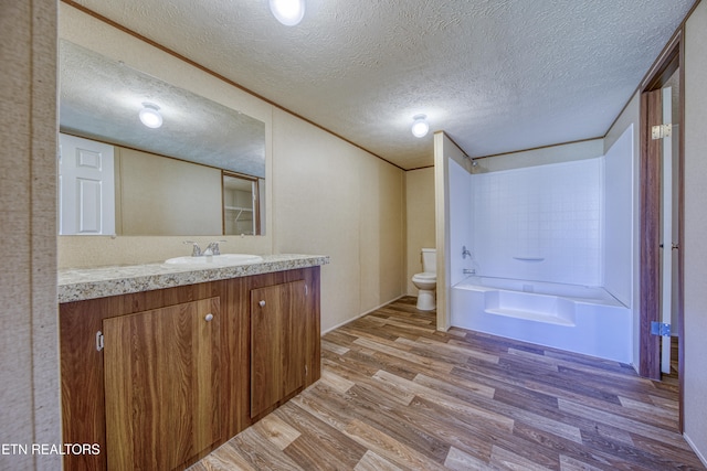 full bathroom with vanity, toilet, a textured ceiling, shower / bathtub combination, and wood-type flooring