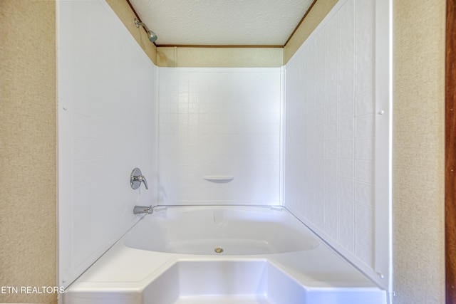 bathroom featuring  shower combination and a textured ceiling