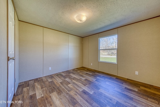 empty room with wood-type flooring and a textured ceiling