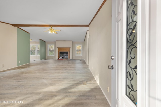 unfurnished living room with ceiling fan, crown molding, and light wood-type flooring