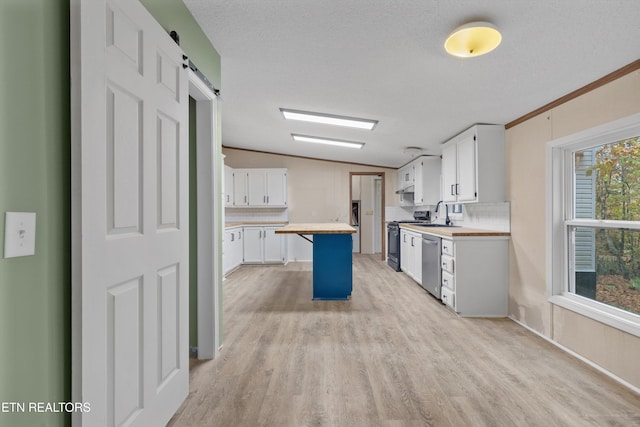 kitchen featuring a center island, wooden counters, a barn door, white cabinetry, and stainless steel appliances