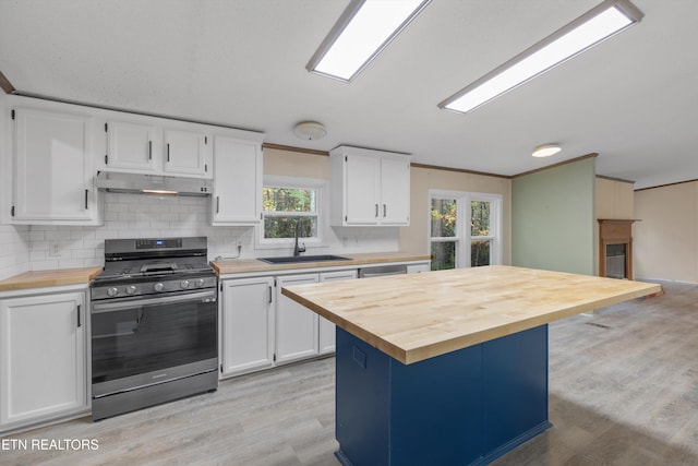 kitchen with butcher block counters, stainless steel range oven, white cabinetry, and a wealth of natural light