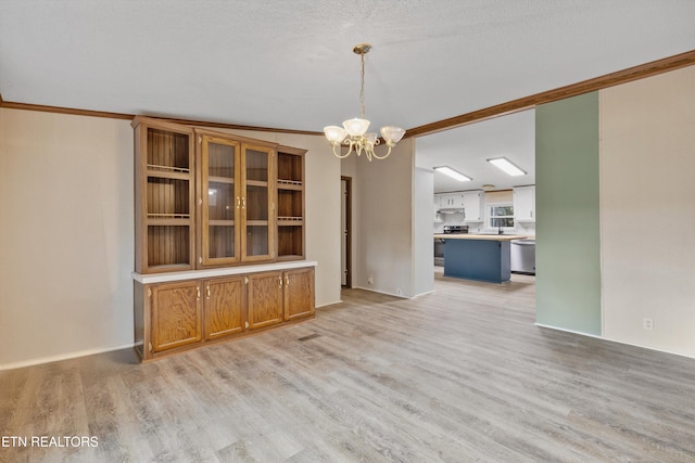 interior space featuring a chandelier, light hardwood / wood-style flooring, and ornamental molding