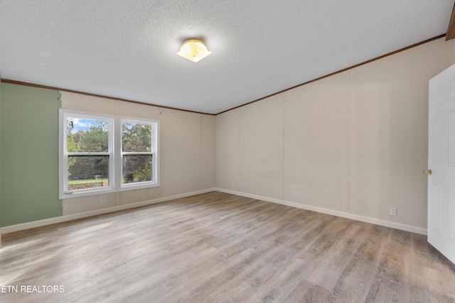 spare room with a textured ceiling, light wood-type flooring, and ornamental molding