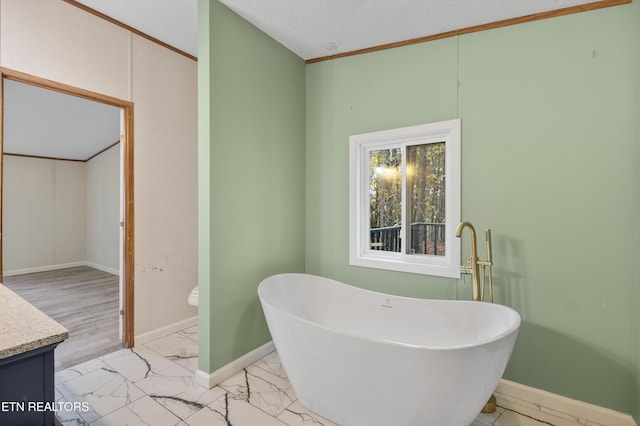 bathroom featuring vanity, a textured ceiling, crown molding, a bath, and toilet