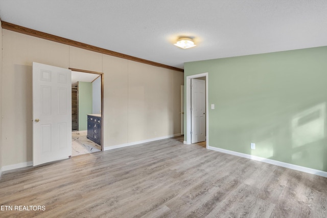 spare room featuring a textured ceiling, light hardwood / wood-style flooring, and ornamental molding