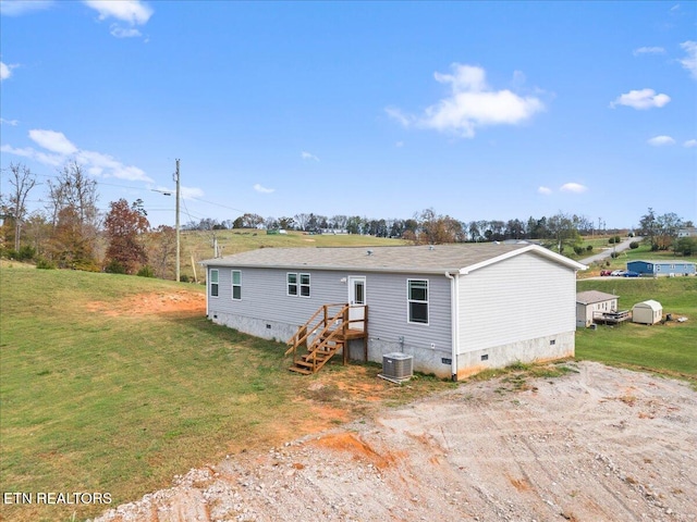 rear view of property featuring central AC unit and a lawn