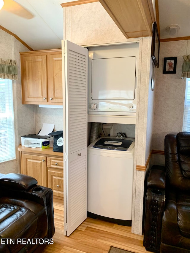 laundry area with crown molding, light hardwood / wood-style flooring, and stacked washing maching and dryer