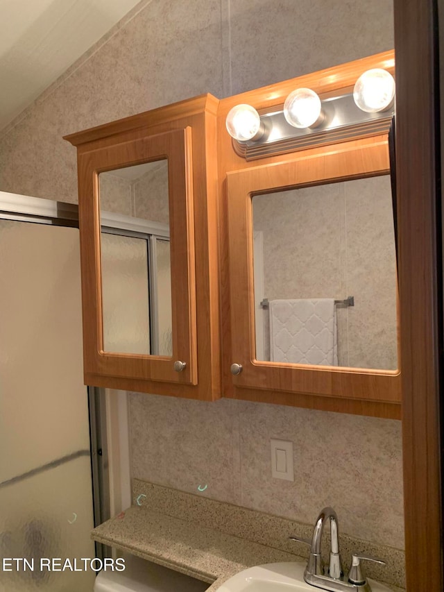 bathroom with a shower with door, sink, and vaulted ceiling