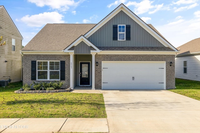 view of front of home with a front yard, central AC, and a garage