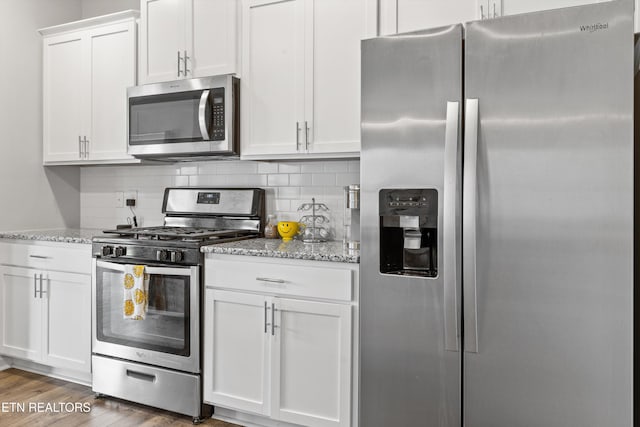 kitchen featuring backsplash, dark wood-type flooring, white cabinets, light stone counters, and stainless steel appliances