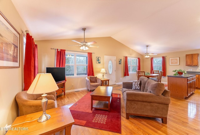 living room featuring a wealth of natural light, light hardwood / wood-style floors, ceiling fan, and vaulted ceiling