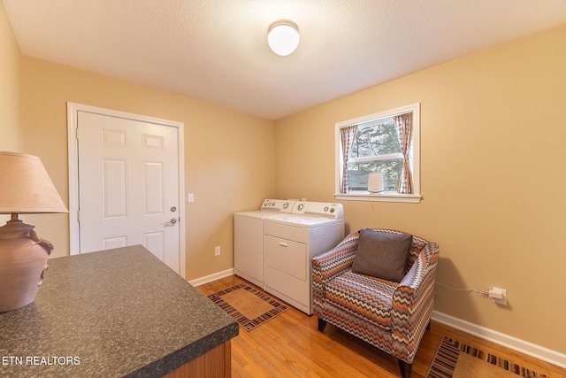 clothes washing area with washer and dryer and light hardwood / wood-style flooring