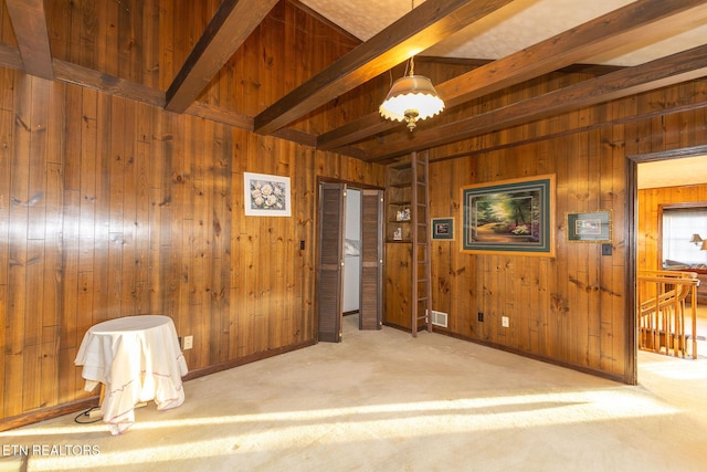 spare room featuring beam ceiling, light colored carpet, and wood walls