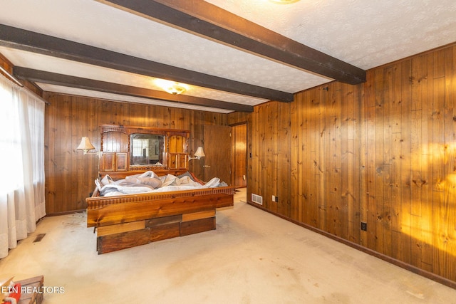 bedroom featuring beam ceiling, light carpet, and wooden walls