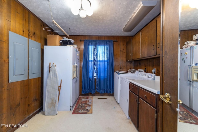 laundry room with wood walls, cabinets, separate washer and dryer, and a textured ceiling