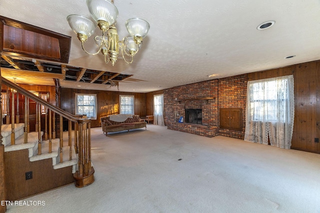 unfurnished living room with a fireplace, carpet, a textured ceiling, and wooden walls