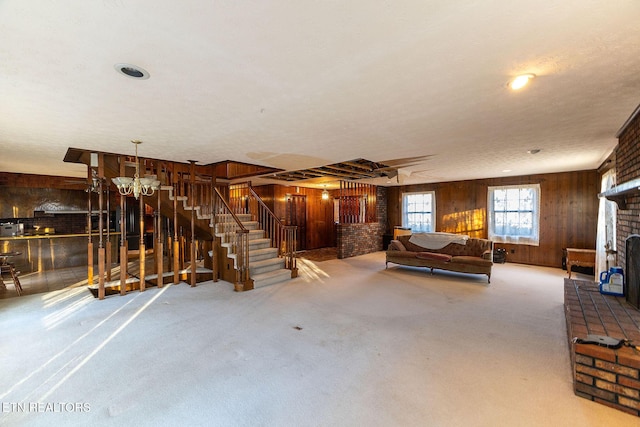 basement with carpet flooring, a textured ceiling, a notable chandelier, a fireplace, and wood walls