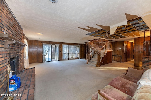 carpeted living room with wood walls, a textured ceiling, and a brick fireplace