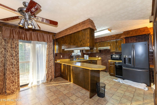 kitchen featuring ceiling fan, range hood, kitchen peninsula, a textured ceiling, and black appliances