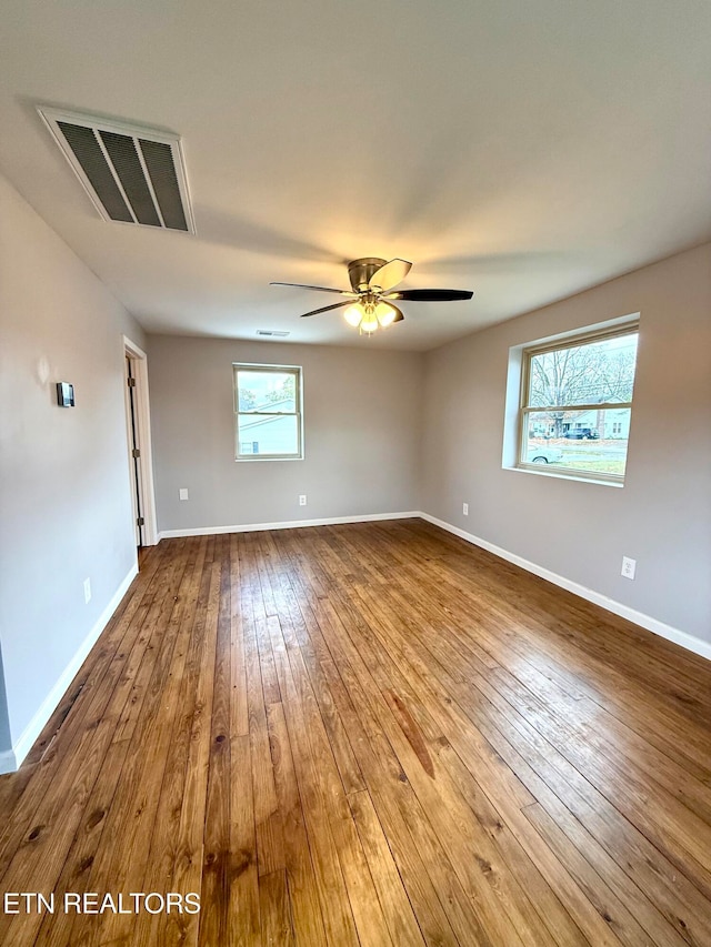 spare room featuring hardwood / wood-style flooring, ceiling fan, and a healthy amount of sunlight