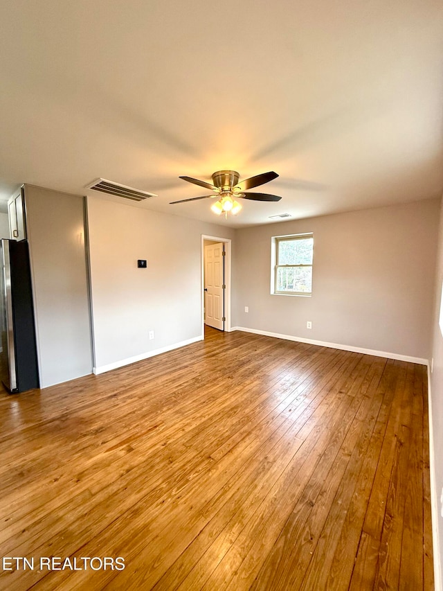 empty room with hardwood / wood-style floors and ceiling fan