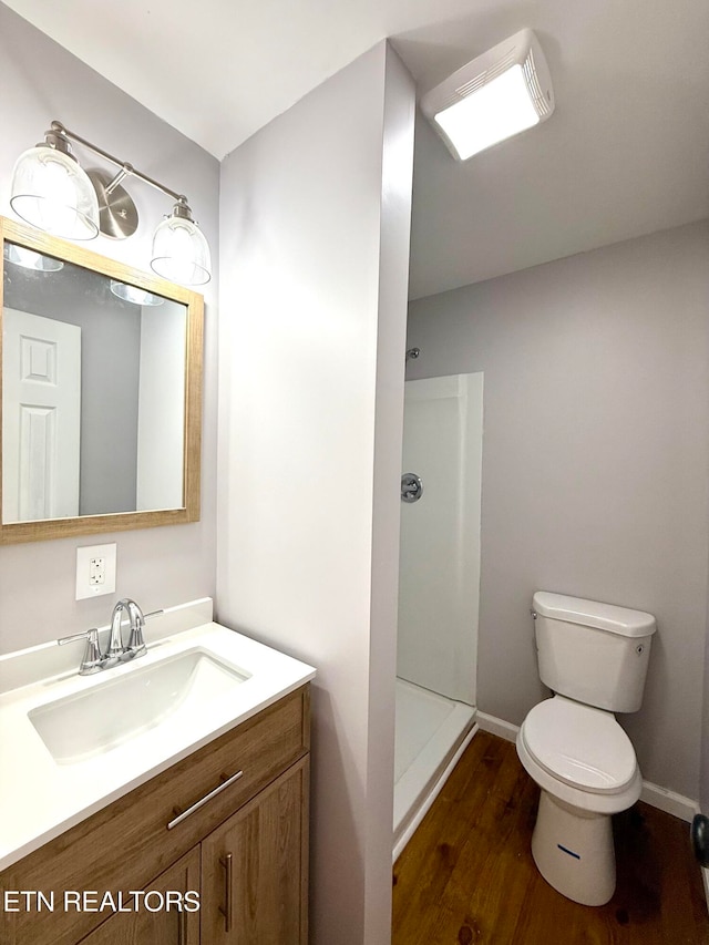 bathroom with toilet, hardwood / wood-style floors, vanity, and walk in shower