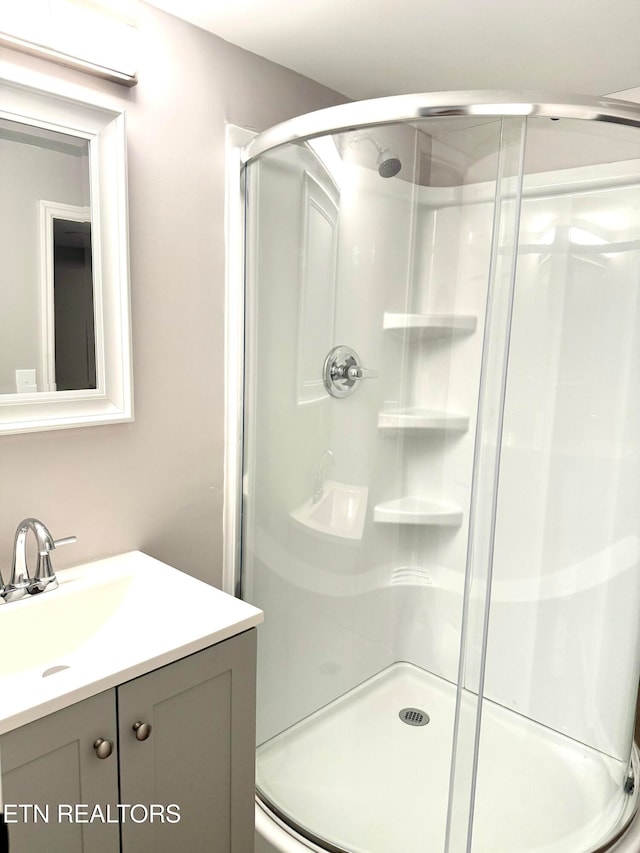 bathroom featuring a shower with door and vanity