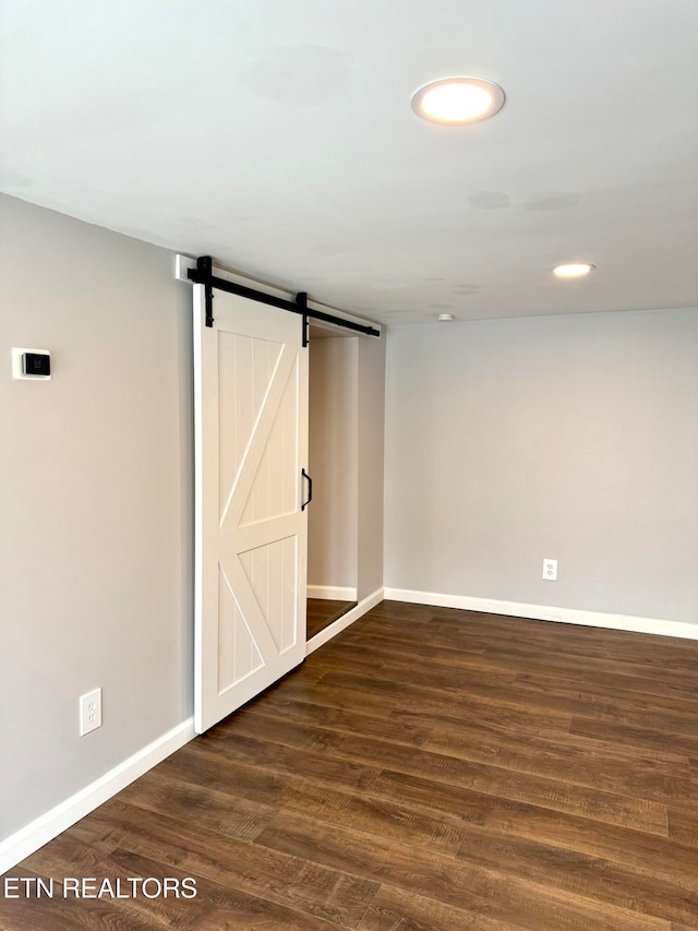 basement with a barn door and dark hardwood / wood-style flooring