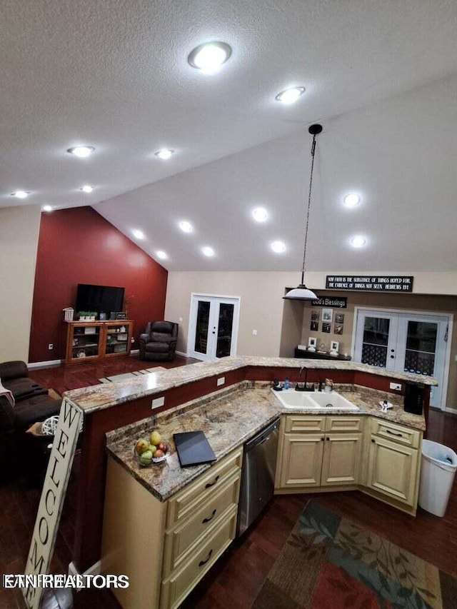 kitchen with dishwasher, sink, vaulted ceiling, cream cabinetry, and decorative light fixtures