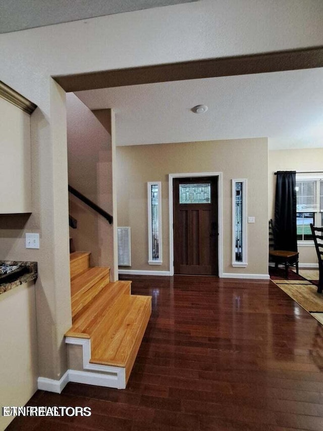 foyer entrance with a textured ceiling and dark wood-type flooring