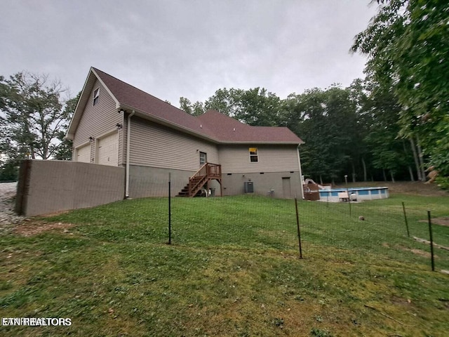 back of house with a fenced in pool, a yard, and a garage