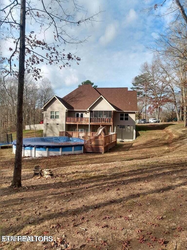 rear view of property featuring a lawn and a swimming pool side deck