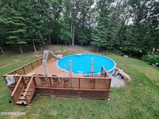 view of pool featuring a yard, a wooden deck, and a water slide