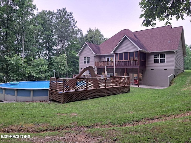 back of house with a sunroom, a pool side deck, and a yard